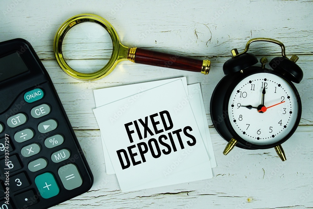 Poster fixed deposits text message on sticky note with magnifying glass, alarm clock and calculator on wood