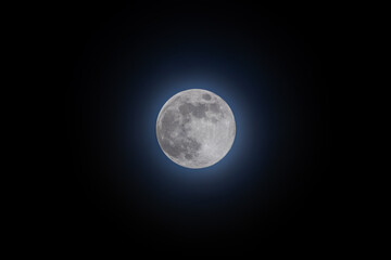 A large, bright full moon is in the sky. The sky is dark and the moon is the only light source