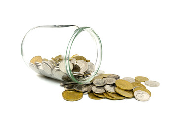 Coins spill from a glass jar on a white background creating a messy display