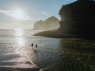 Couple and dog enjoy a scenic Bethells Beach walk at sunset. Coastal scenery. Bethells Beach,...