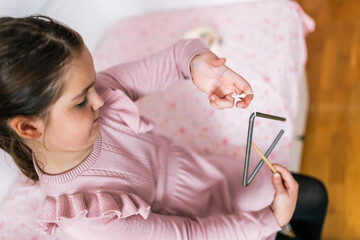 Closeup of girls hands playing triangle.