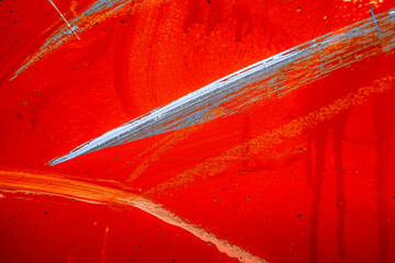Messy paint strokes and smudges on an old red grunge wall background. White, black, orange color...