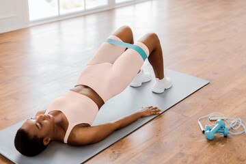 Fitness Concept. Athletic sporty woman in white sportswear training with elastic resistance band...