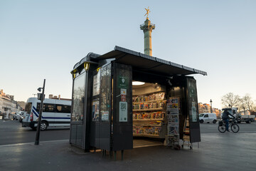 Newspaper kiosk stands at Place de la Bastille in Paris during early evening