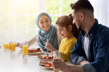 Lunch Together. Happy Islamic Parents And Little Daughter Enjoying Tasty Food In Kitchen, Cheerful...
