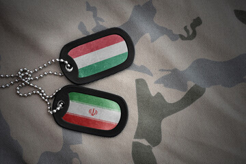 vintage army blank, dog tag with flag of hungary and iran on the khaki texture background. military...
