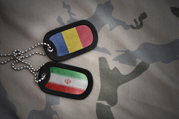 vintage army blank, dog tag with flag of romania and iran on the khaki texture background. military...