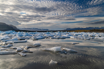 Clouds reflect calving glacial ice in Fjallsarlon Lagoon, Iceland
