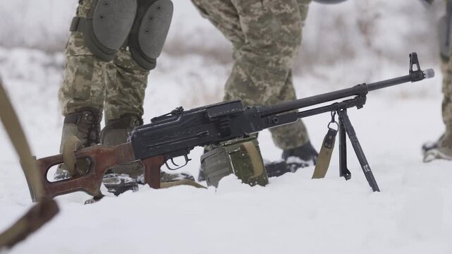 Soldier takes a light machine gun on a mission. A special forces group prepares to go on a special operation in winter. A machine gun against the background of snow. Winter military special operation