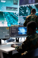 Military experts in a mission control center use modern technology on computer and big screen,...