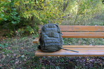 Green backpack on a wooden bench. Nature photo.