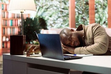 Small business owner feels tired and takes a nap while doing remote work, sleeping on his home desk. Stressed overworked freelancer falling asleep at the office setup, financial operations.