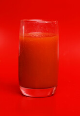 glass of tomato juice on red background