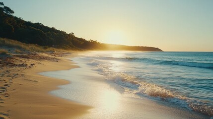 Serene sunrise over sandy beach with gentle waves.