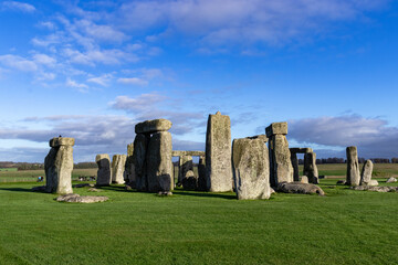 Fototapeta premium A majestic view of Stonehenge, the ancient megalithic monument in Wiltshire, England. Captured under a vibrant blue sky, the iconic stones stand