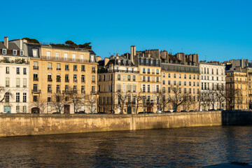 Beautiful riverside buildings along the calm water under a clear blue sky