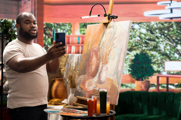 African american artist recording an online promotion video to present his new creation, using his online presence for social media reach and engagement. Advertising campaign for branding.