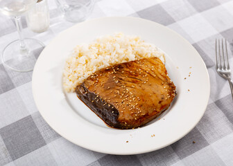 Portion of just cooked tuna fillet garnished with boiled rice and served on table with sesame seeds.