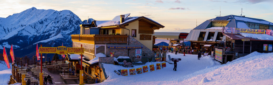 Piani di Bobbio, Italy - 24.12.2022: Panoramic view of mountain restaurant and skiers. Snow-covered peaks, cozy dining area and ski resort activity. Mountain alpine ski resort near Lecco, Italy