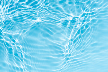 Blue water with ripples on the surface. Defocus blurred transparent blue colored clear calm water surface texture with splashes and bubbles. Water waves with shining pattern texture background.