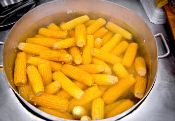 Corn being cooked inside a large metal pan. street food
