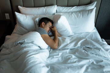 Young sleepless man lying in bed feeling tired stressed	