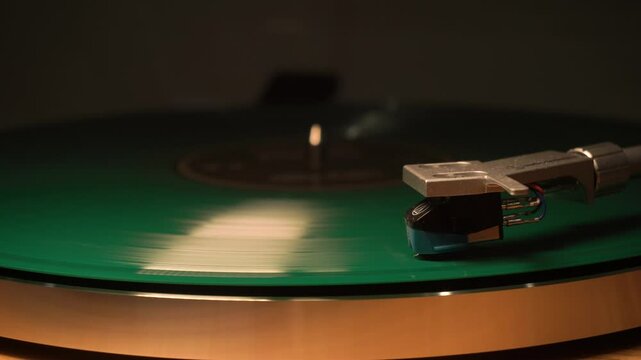a green vintage musical vinyl record is playing. The needle glides smoothly on the plate, plays music. close-up.