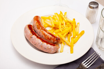 Appetizing grilled sausages served with fried potato on plate