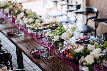 Luxurious dining table setup with flowers, appetizers, and wine glasses for an elegant celebration