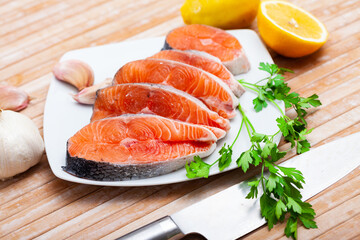 Closeup of fresh organic cutting salmon seafood with herbs and lemon on a table
