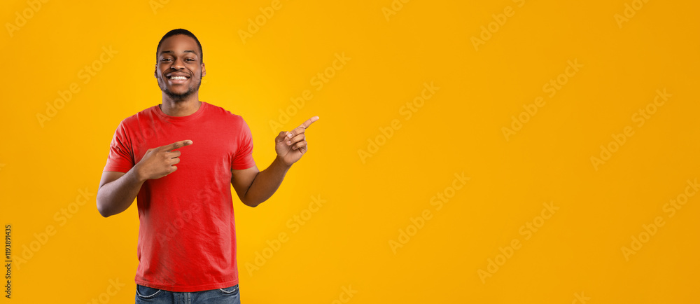 Poster look there. cheerful african american man pointing fingers aside showing empty space for text posing