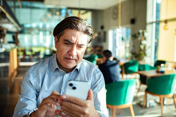 Businessman using smartphone in modern cafe