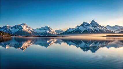 Serene sunrise over a tranquil lake reflecting snow-capped mountain peaks