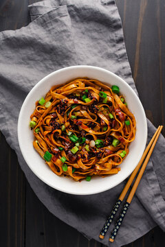 Shallot Chili Oil Noodles Served in a Ramen Bowl: Hot and spicy lo mein noodles topped with chili crisp and scallions served with chopsticks