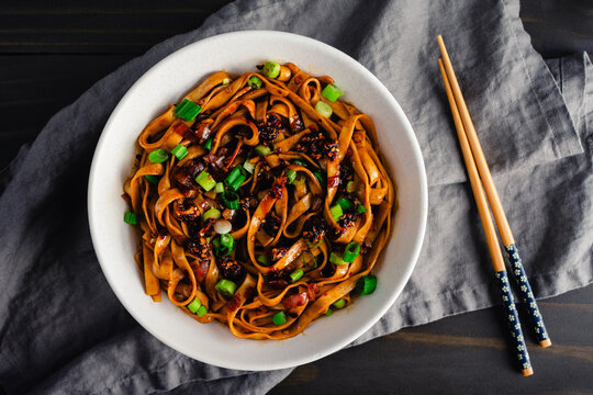 Shallot Chili Oil Noodles Served in a Ramen Bowl: Hot and spicy lo mein noodles topped with chili crisp and scallions served with chopsticks