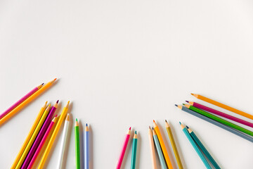 Fototapeta premium Сolored pencils on a white background. Copy space, mockup, flat lay. Art, creativity, education concept