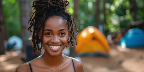 Black Woman Smiling at a Campsite with Tents in the Background