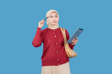 A woman wearing a red sweater and a tan head scarf is holding a pen tablet and looking up. She is...
