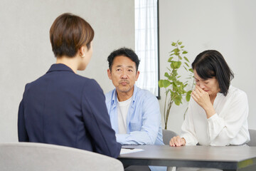Fototapeta premium 泣きながらビジネスウーマンに相談する夫婦