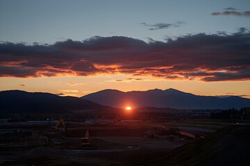 Dramatic sunset over a construction site with mountains in the background.  Perfect for construction, industry, or nature imagery.