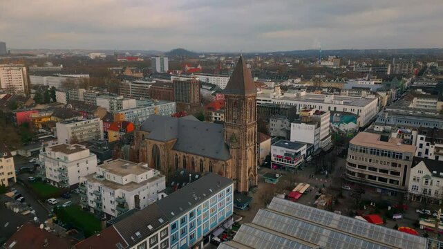 Bird's-eye view of Oberhausen, Germany, highlighting the majestic church tower set against a background of bustling city life and diverse architecture, reflecting both historic and modern influences