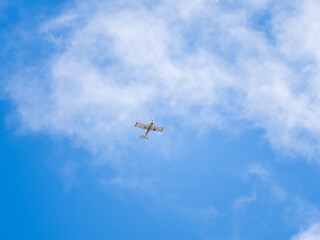 Small ultralight airplane with overhead wing and single propeller flying in sunset sky.