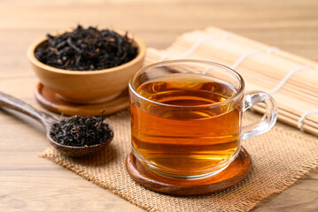 Black tea in cup glass with dried tea leaves, Healthy herbal drink