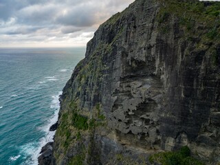 Dramatic coastal cliff face, sculpted by the ocean. Waves crash against the rocky shore. Nature's...