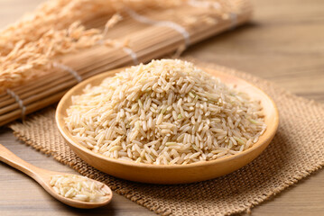 Organic Jasmine brown rice seed on wooden plate with spoon, Thai Rice