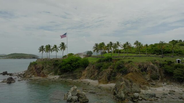 Aerial: Drone Forward Flag Of The United States On Epstein Island Under Cloudy Sky - VI, 
Little Saint James, United States of America
