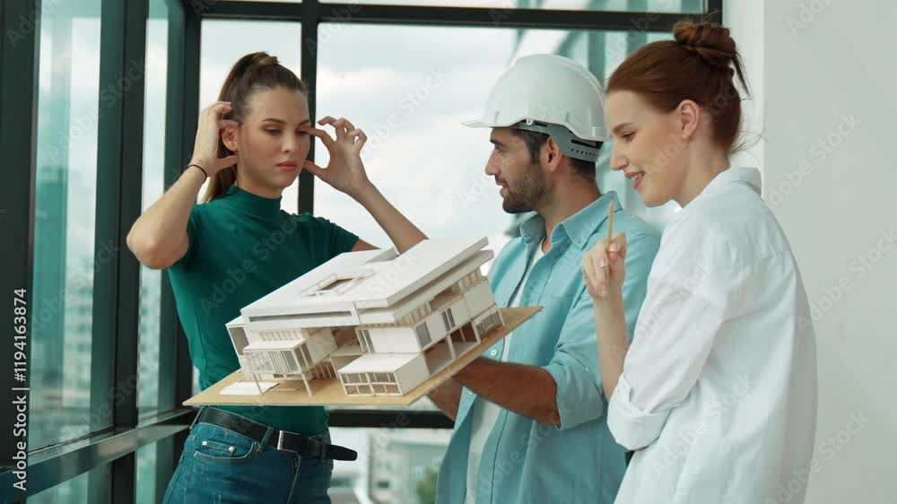 Poster project manager holds house model while architect engineer team share, brainstorm, discuss about hou