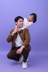 Young Asian father and daughter on purple background