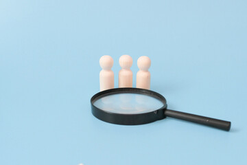 Wooden doll with Magnifying glass. Representing  finding talent positions for various purposes.  Human Resource Management and Recruitment and Hiring concept. Find leader. Find team.