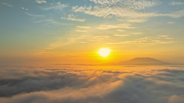 A serene view of the early morning sun rising above a vast sea of clouds, with distant mountain peaks faintly visible on the horizon, creating a peaceful and ethereal landscape. Flying over the cloud